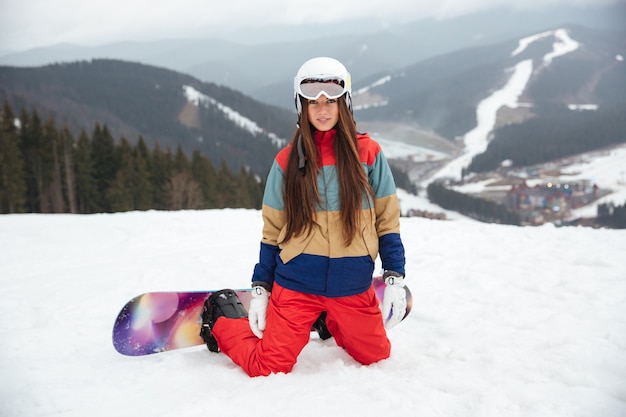 Young lady snowboarder sitting on the slopes frosty winter day