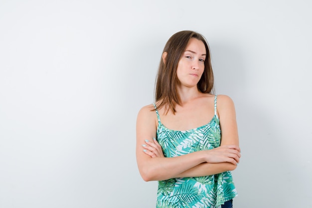 Young lady standing with crossed arms and looking sensible , front view.