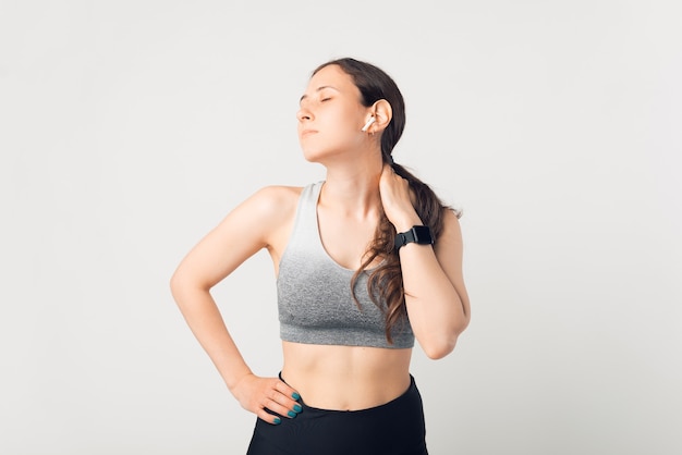 Young lady wearing sportswear is taking a break because of her neck aches.