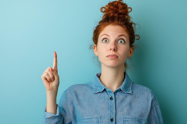 Photo young lady with ginger hair wearing blue shirt and pointing finger up