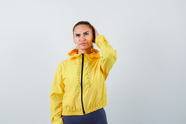 Young lady with hand on head in tracksuit and looking thoughtful , front view.