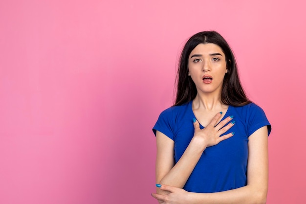 Young lady you holding her hand to her chest and looking at the camera with open mouth High quality photo