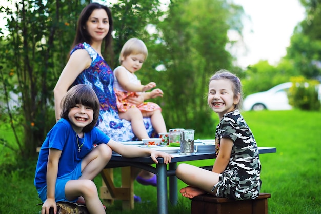 A young large family at a picnic on a summer morning. A beautiful mother with children is having breakfast in the park.