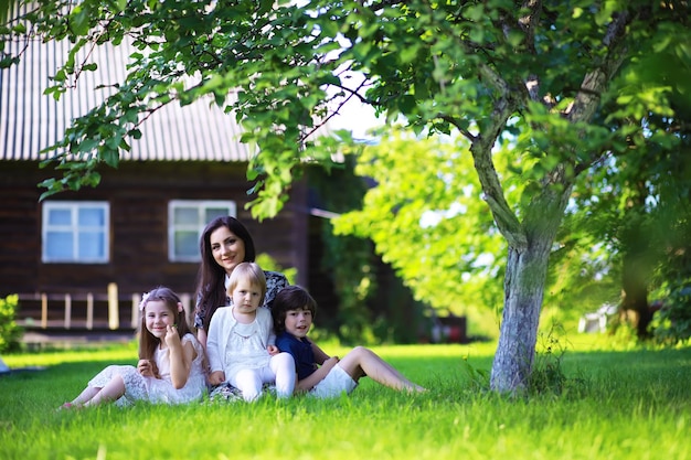 Young large family on a summer morning walk. Beautiful mother with children is playing in the park.