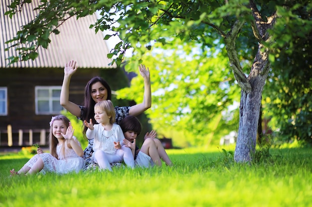 Young large family on a summer morning walk. Beautiful mother with children is playing in the park.