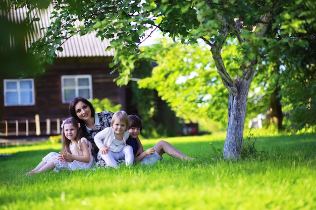 Young large family on a summer morning walk. Beautiful mother with children is playing in the park.