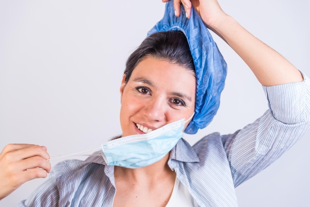 Young Latin American doctor contentedly removing her cap and mask doctors investigating an infection