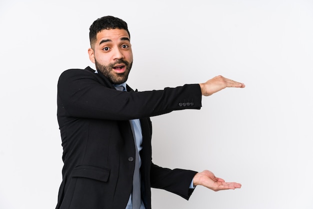 Young latin business woman against a white background isolated shocked and amazed holding a copy space between hands.