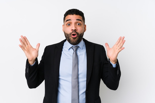 Young latin business woman against a white surface isolated celebrating a victory or success, he is surprised and shocked.