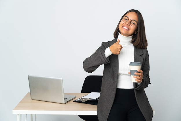 Young latin business woman working in a office isolated on white background giving a thumbs up gesture