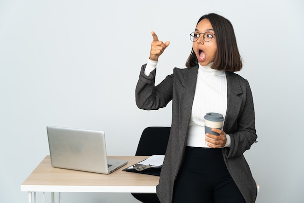 Young latin business woman working in a office isolated on white background pointing away