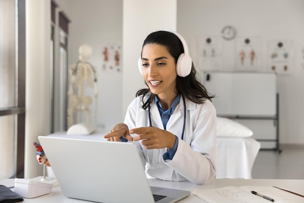 Young Latin doctor in headphones speaking on video conference call