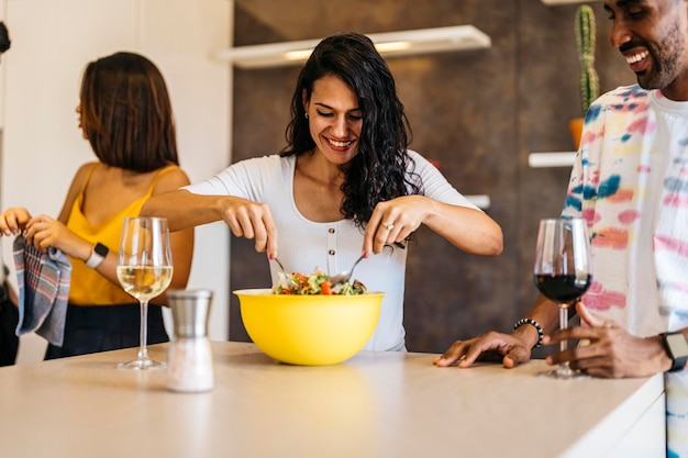 Young Latin girl stirring salad next to Latin guy in the kitchen