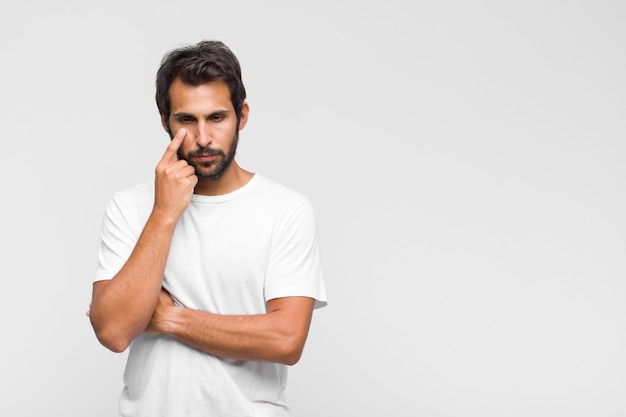 Young latin handsome man keeping an eye on you, not trusting, watching and staying alert and vigilant