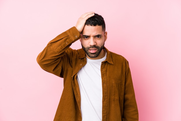 Young latin man against a pink isolated tired and very sleepy keeping hand on head.