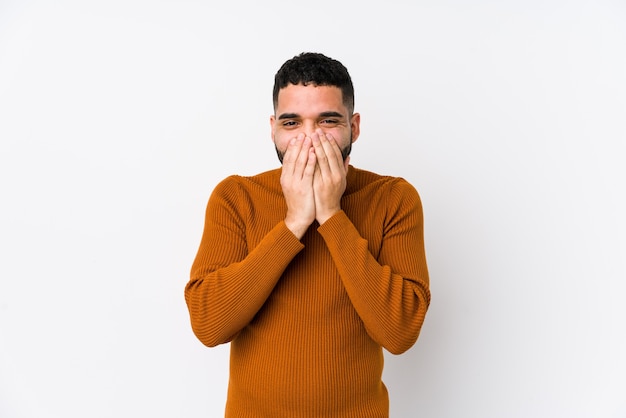 Young latin man against a white background isolated laughing about something, covering mouth with hands.