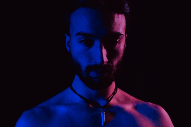 Young latin man looking at camera with confidence pink and blue light studio photo