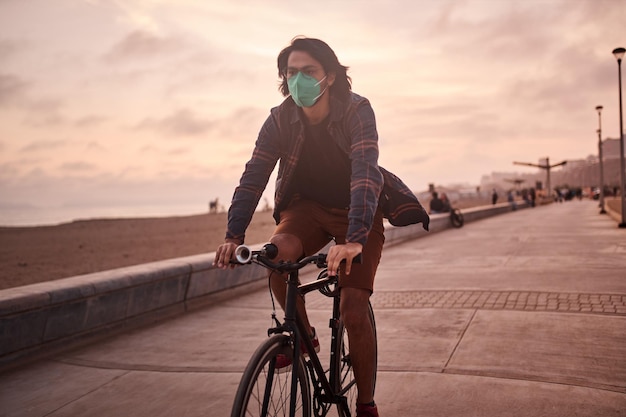 Young Latin man rides a bicycle during a beautiful sunset