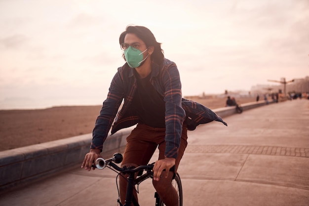 Young Latin man rides a bicycle during a beautiful sunset