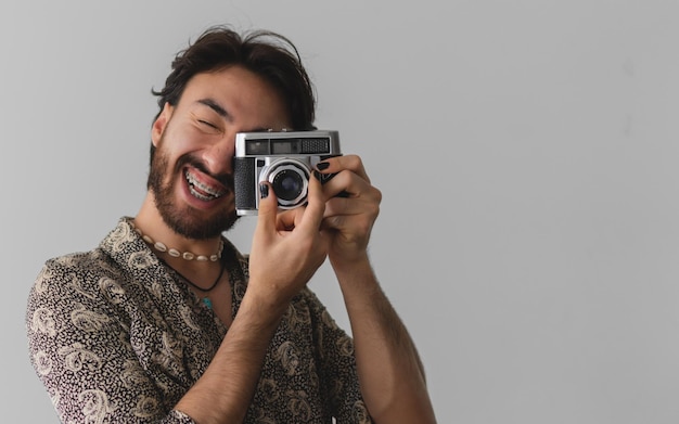 Young latin man smiling taking pictures with painted nails on a white background Copy space