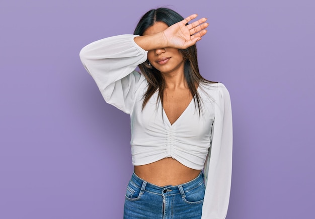 Young latin transsexual transgender woman wearing casual clothes covering eyes with arm looking serious and sad sightless hiding and rejection concept