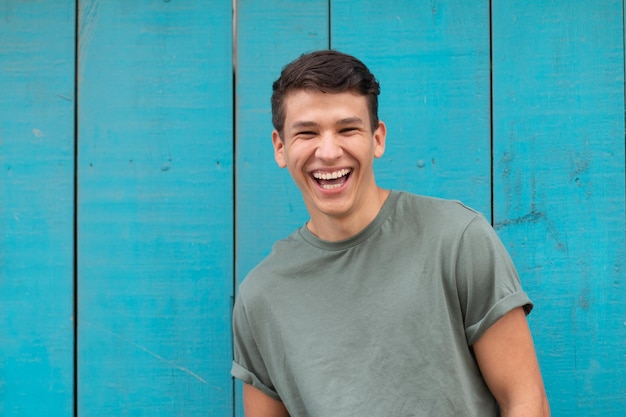 Young latin with an authentic laugh, in the background a blue door typical of latin homes.