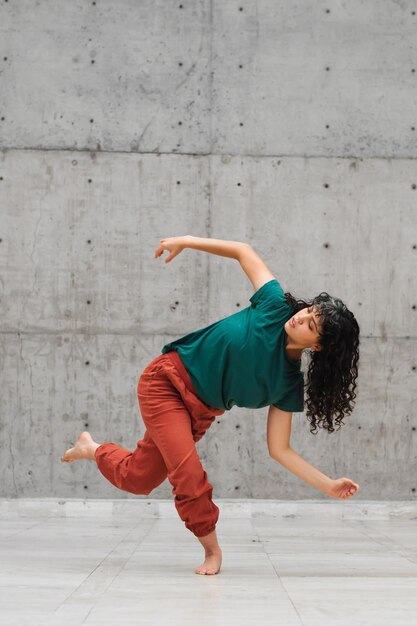 Photo a young latin woman dancing in an empty stage