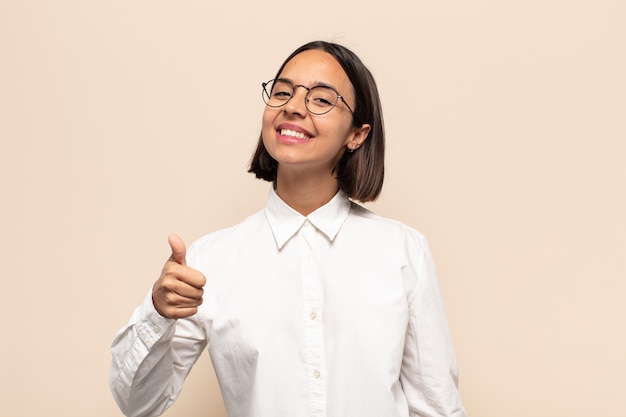 Young latin woman feeling proud, carefree, confident and happy, smiling positively with thumbs up