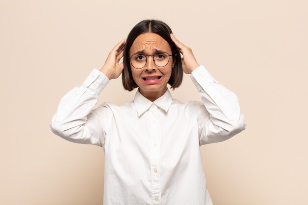 Young latin woman feeling stressed, worried, anxious or scared, with hands on head, panicking at mistake