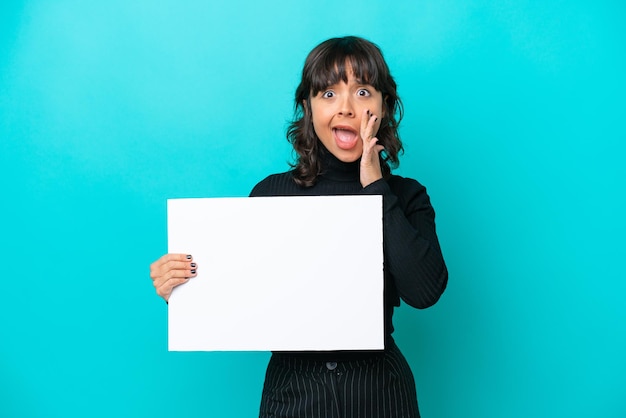 Young latin woman isolated on blue background holding an empty placard and shouting