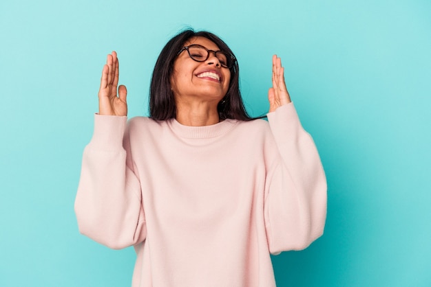 Young latin woman isolated on blue background joyful laughing a lot. Happiness concept.