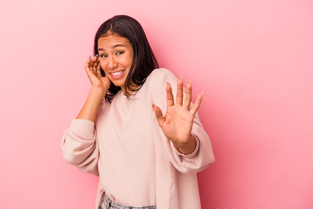 Young latin woman isolated on pink background  being shocked due to an imminent danger