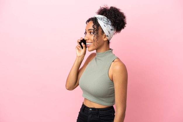 Young latin woman isolated on pink background keeping a conversation with the mobile phone with someone