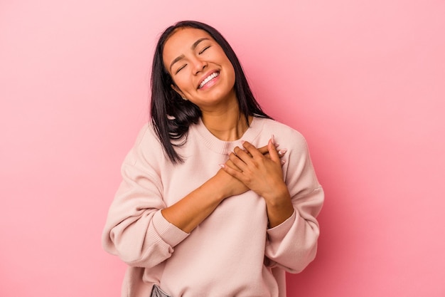 Young latin woman isolated on pink background  laughing keeping hands on heart concept of happiness