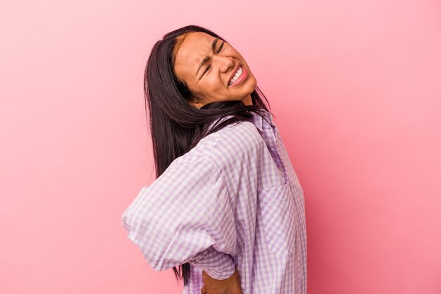 Young latin woman isolated on pink background  suffering a back pain.