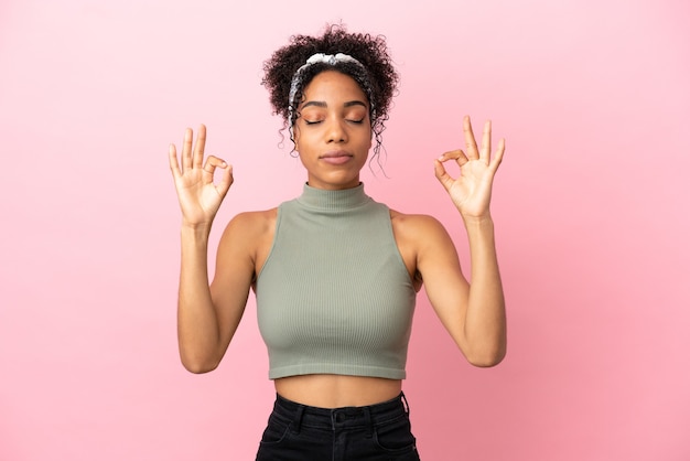 Young latin woman isolated on pink background in zen pose