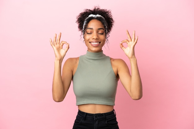 Young latin woman isolated on pink background in zen pose