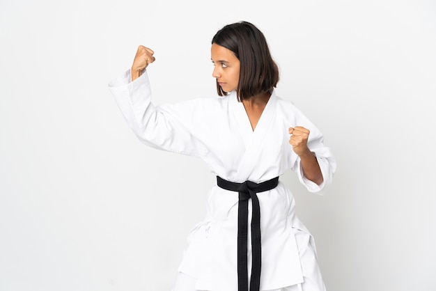 Young latin woman isolated on white background doing karate