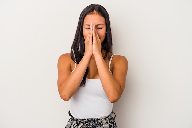 Young latin woman isolated on white background  holding hands in pray near mouth, feels confident.