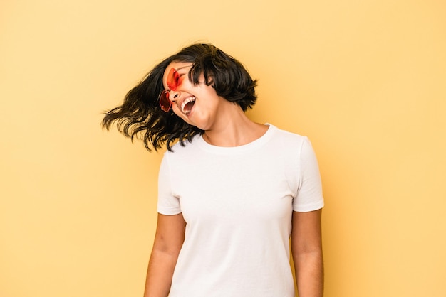 Young latin woman isolated on yellow background dancing and having fun.