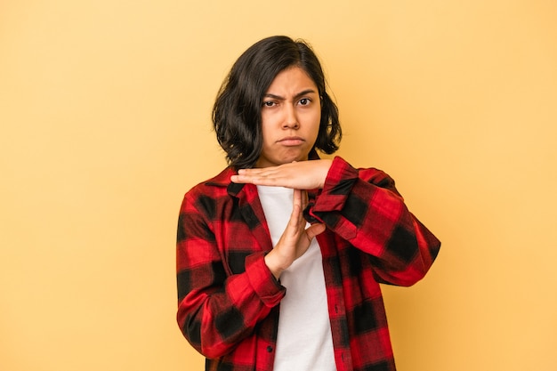 Young latin woman isolated on yellow background showing a timeout gesture.