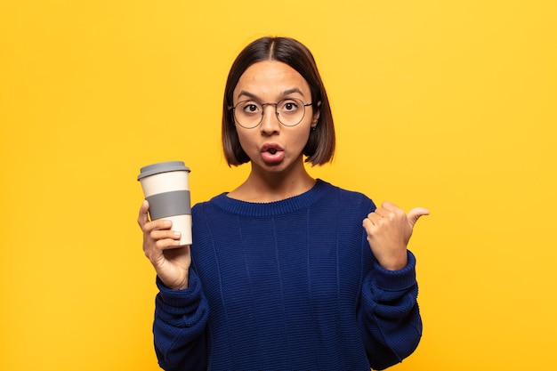 Young latin woman looking astonished in disbelief, pointing at object on the side and saying wow, unbelievable