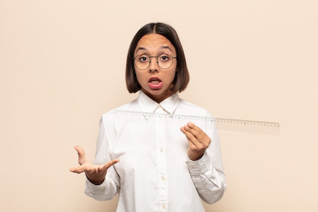 young latin woman open-mouthed and amazed, shocked and astonished with an unbelievable surprise