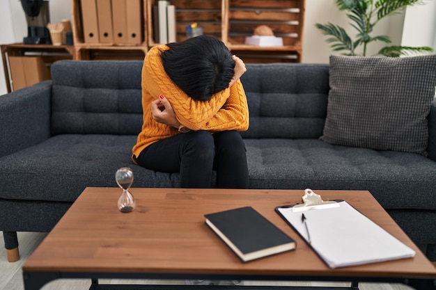 Young latin woman patient having psychology session crying at clinic