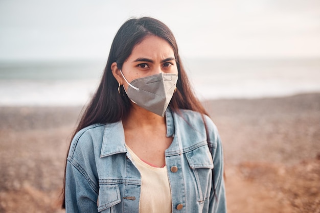 Young latin woman poses walking on the sand during a beautiful sunset Happy young woman with mask