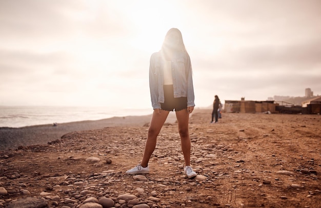 Young latin woman poses walking on the sand during a beautiful sunset Happy young woman with mask