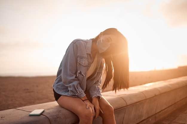 Young latin woman poses walking on the sand during a beautiful sunset Happy young woman with mask