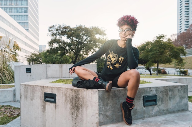 Young latin woman sitting in the square leaning on her hand bored thinking looking at the camera