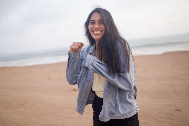 Young Latin woman smiles during a beautiful sunset Happy young woman with mask on the beach taking