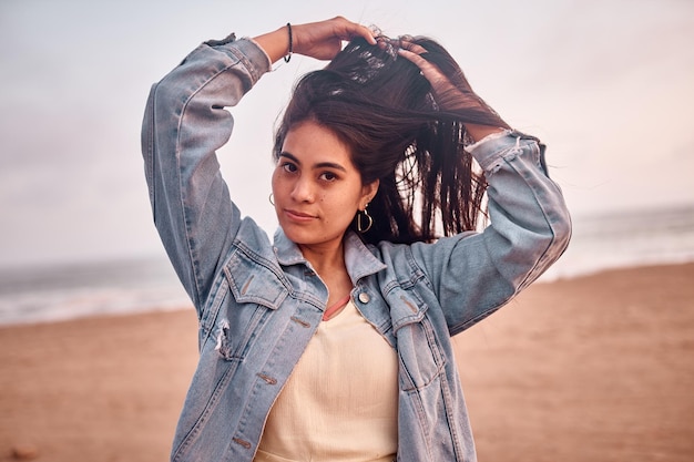 Young Latin woman smiles during a beautiful sunset Happy young woman with mask on the beach taking